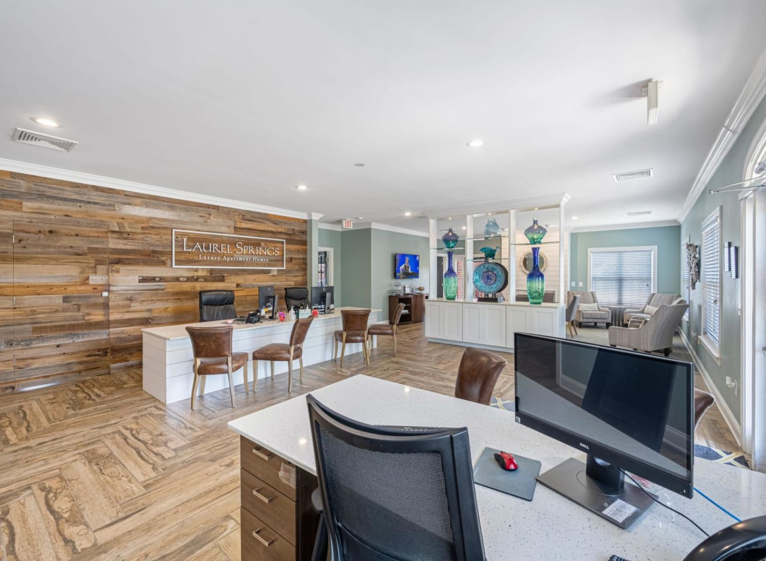 Modern office lobby with wood accents, reception desk, computer stations, and lounge seating area.