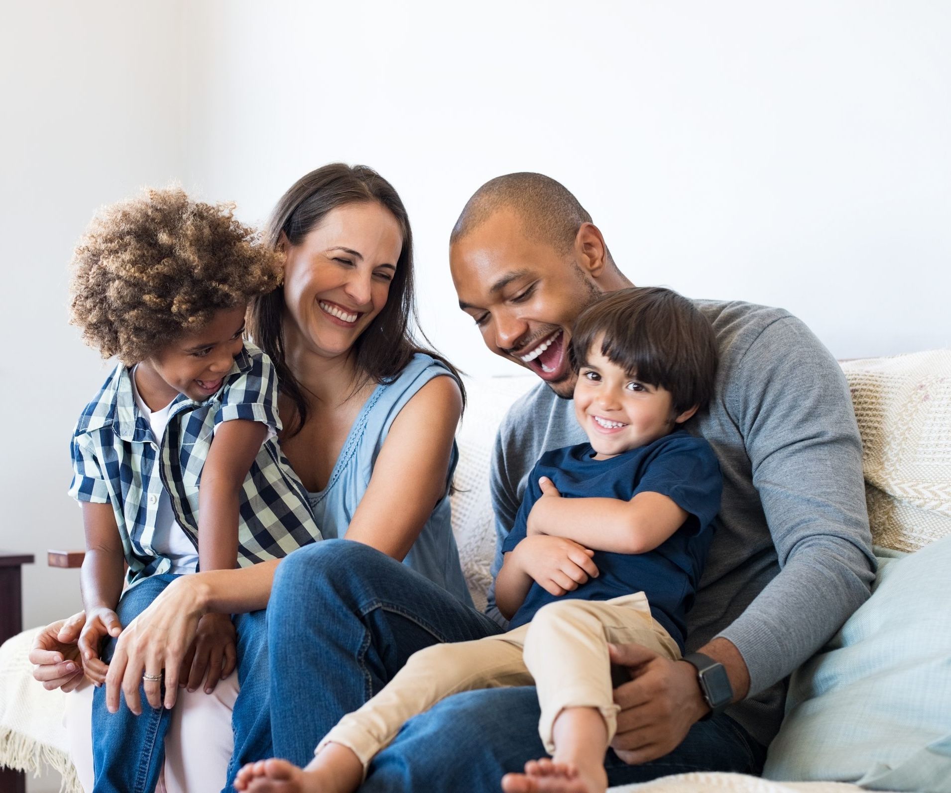Smiling family of four sitting on a couch, laughing and enjoying time together.